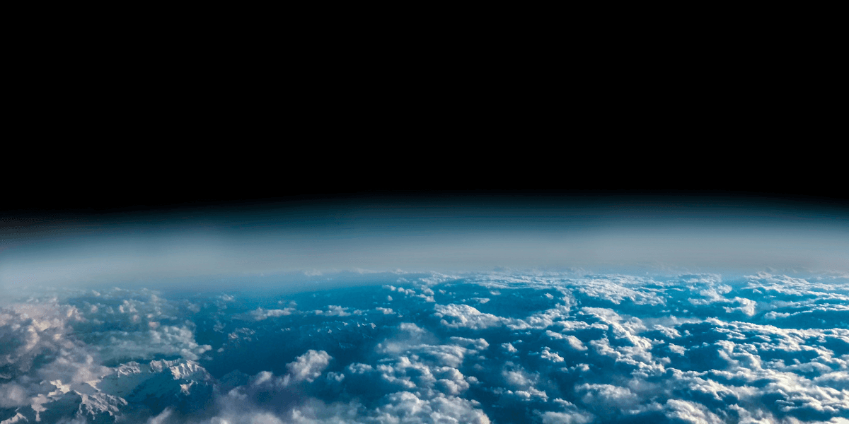 A view of Earth from space showing clouds and the horizon against blackness