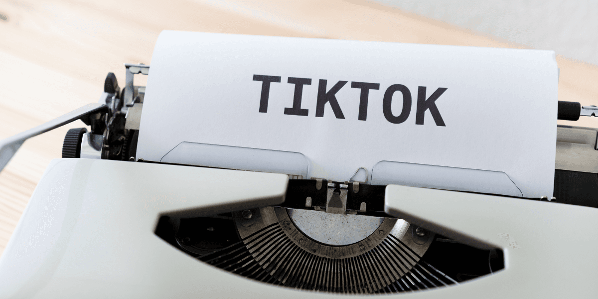A vintage typewriter printing the word TIKTOK on a sheet of paper
