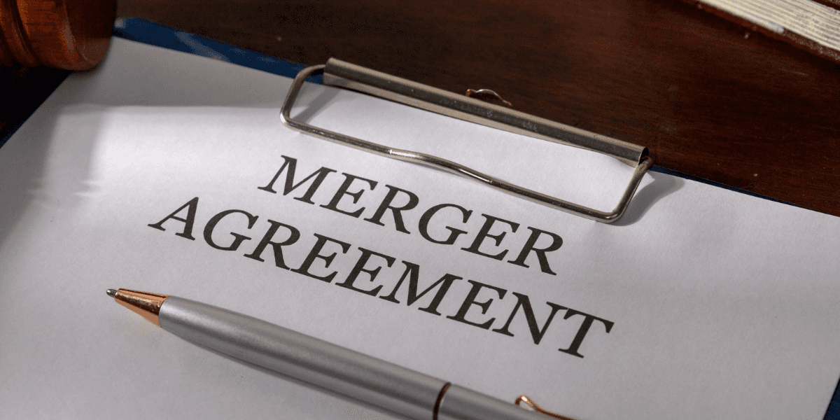 Merger agreement document with a pen and a clipboard on a desk