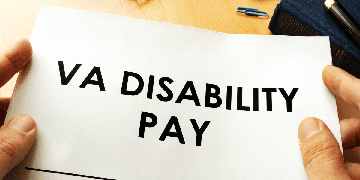 Person holding a paper with the words VA DISABILITY PAY in bold text