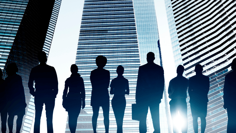 Silhouettes of diverse business people standing against a backdrop of tall skyscrapers