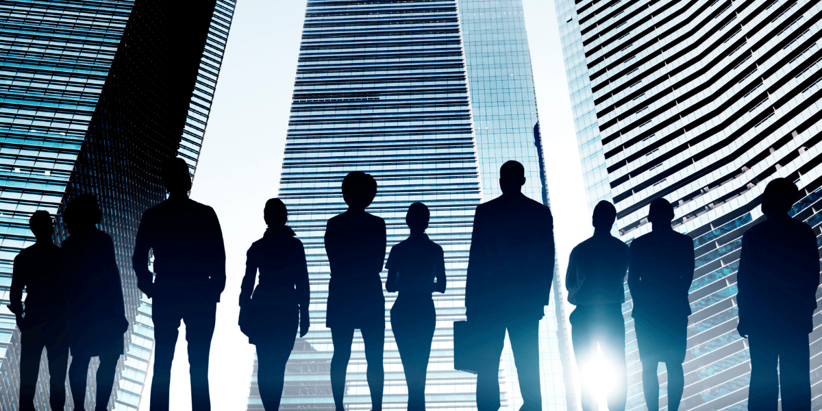 Silhouettes of diverse business people standing against a backdrop of tall skyscrapers