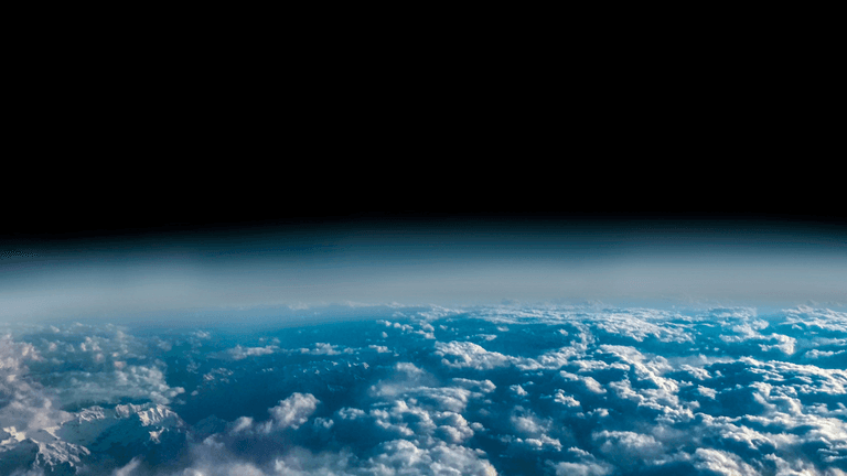 A view of Earth from space showing clouds and the horizon against blackness
