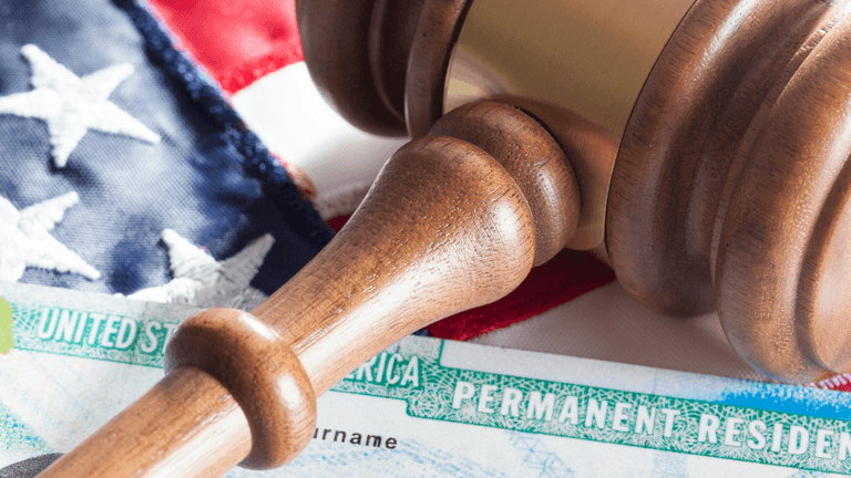 A gavel resting on an American flag with a permanent resident card nearby