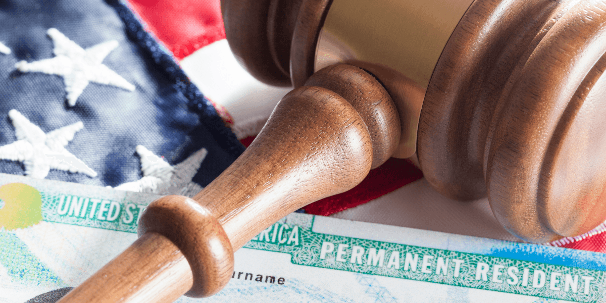 A gavel resting on an American flag with a permanent resident card nearby