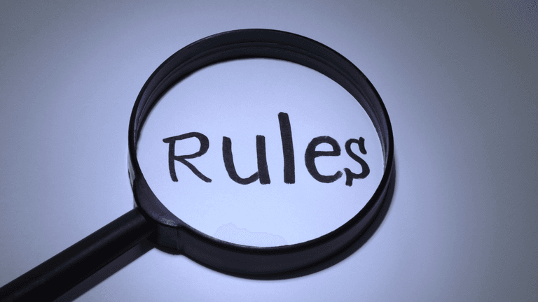 A magnifying glass highlighting the word "Rules" on a white surface