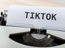 A vintage typewriter printing the word TIKTOK on a sheet of paper