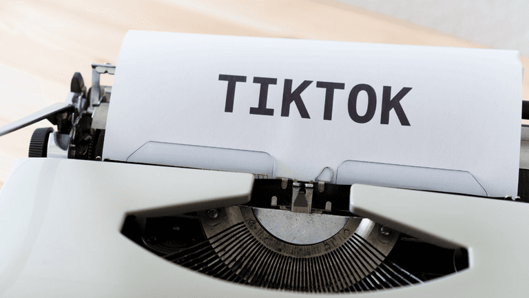 A vintage typewriter printing the word TIKTOK on a sheet of paper