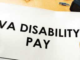 Person holding a paper with the words VA DISABILITY PAY in bold text