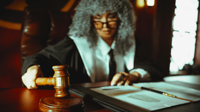 Judge holding a gavel while reviewing legal documents in a courtroom.