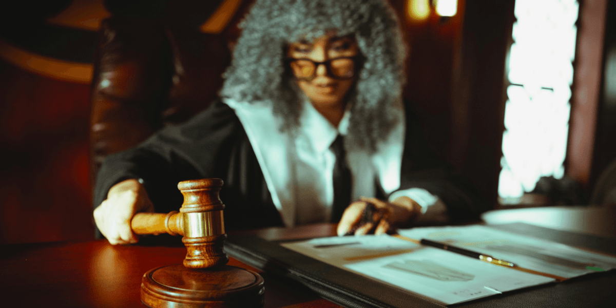 Judge holding a gavel while reviewing legal documents in a courtroom.