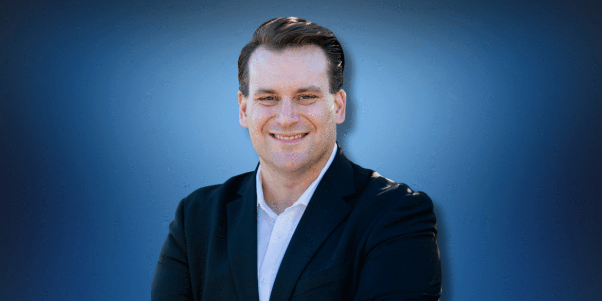 Man in a suit smiling confidently, representing attorney Travis Vernier of Bennett | Vernier law firm.