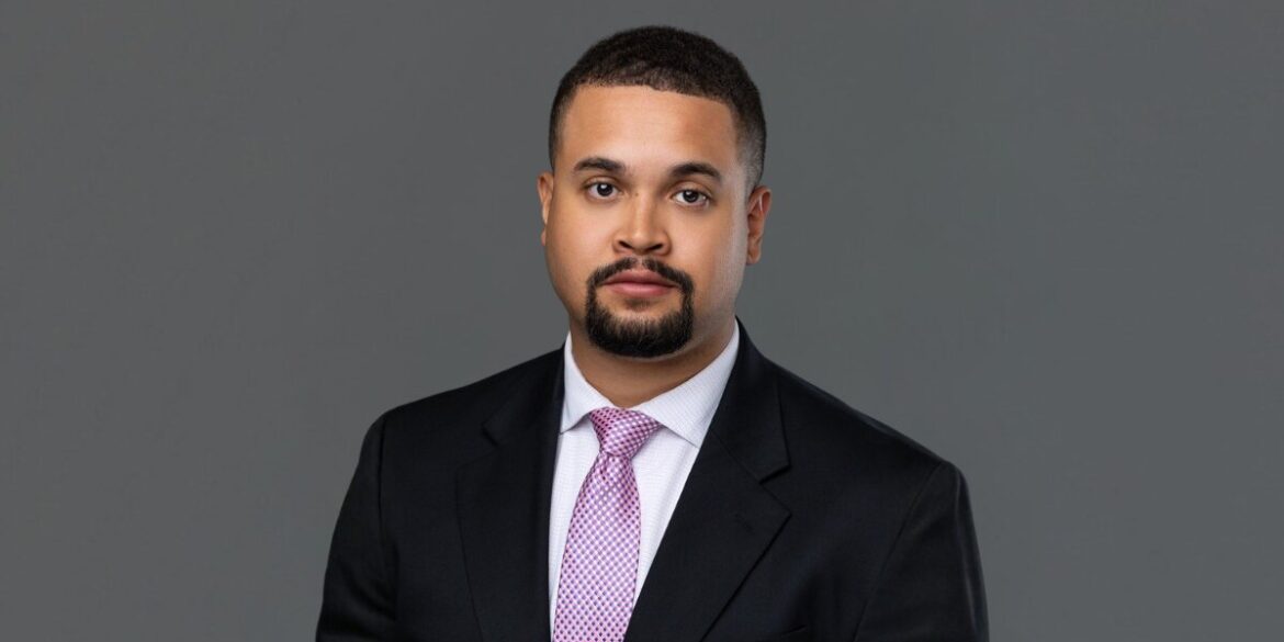 Professional headshot of Associate Attorney Zachary E. Levi wearing a dark suit and pink tie against a gray background.