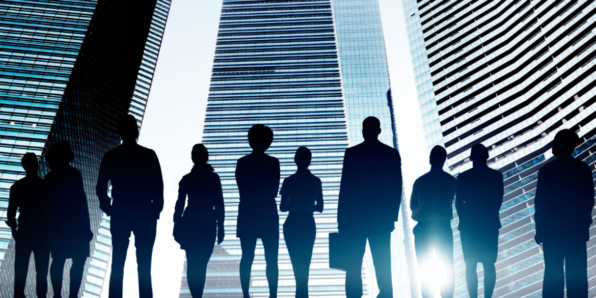 Silhouettes of business professionals standing against modern glass skyscrapers in an urban corporate setting.